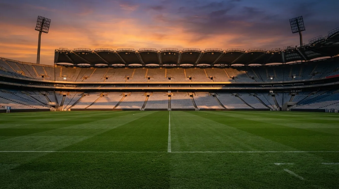 Un estadio de fútbol vacío con torres de iluminación al atardecer