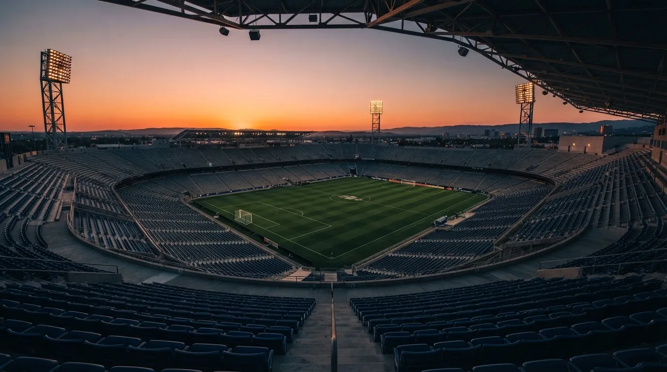 Un estadio de fútbol vacío con torres de iluminación al atardecer