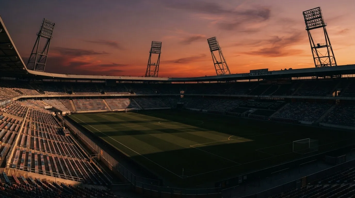 Un estadio de fútbol vacío con torres de iluminación al atardecer
