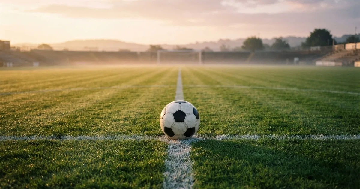 Un balón en el punto central de un campo de césped a la luz de la mañana