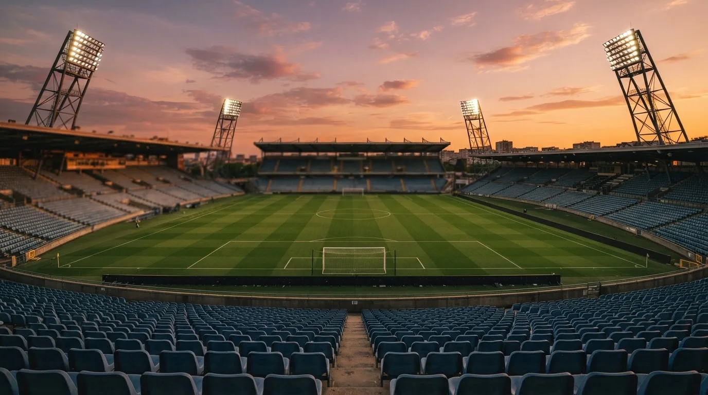 Un estadio de fútbol vacío con torres de iluminación al atardecer