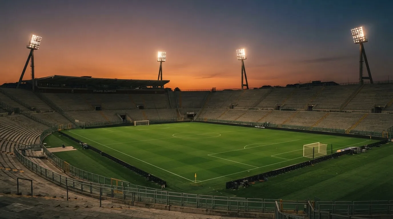 Un estadio de fútbol vacío con torres de iluminación al atardecer