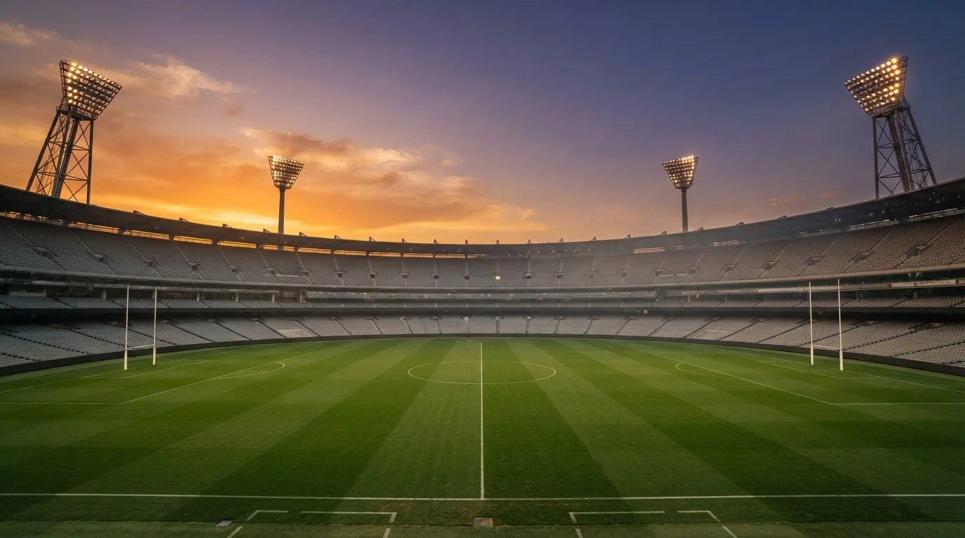 Un estadio de fútbol vacío con torres de iluminación al atardecer