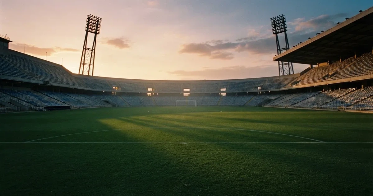 Un estadio de fútbol vacío con torres de iluminación al atardecer