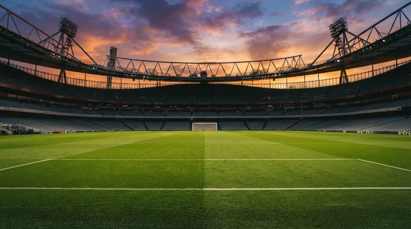 Un estadio de fútbol vacío con torres de iluminación al atardecer