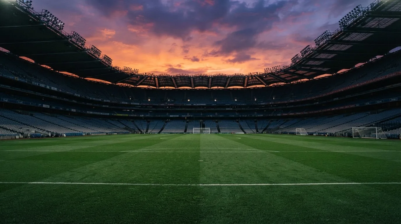 Un estadio de fútbol vacío con torres de iluminación al atardecer