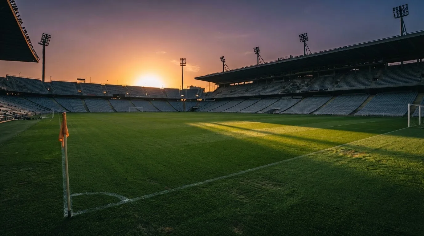 Un estadio de fútbol vacío con torres de iluminación al atardecer