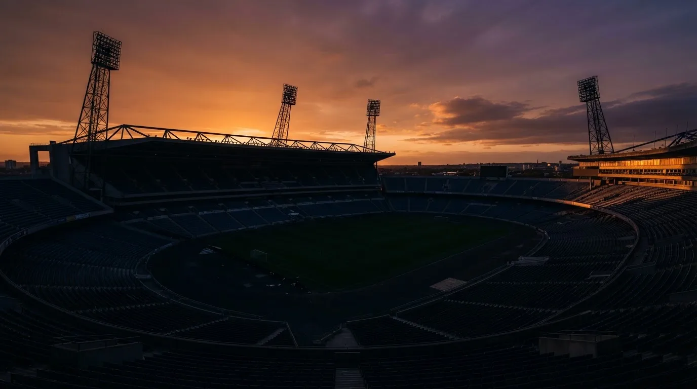 Un estadio de fútbol vacío con torres de iluminación al atardecer