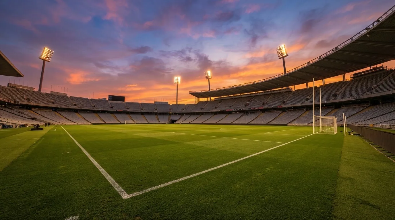 Un estadio de fútbol vacío con torres de iluminación al atardecer