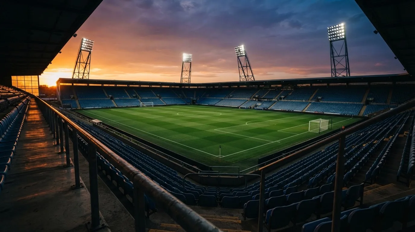 Un estadio de fútbol vacío con torres de iluminación al atardecer