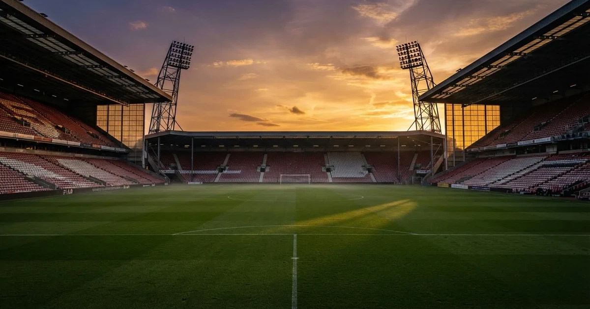 Un estadio de fútbol vacío con torres de iluminación al atardecer
