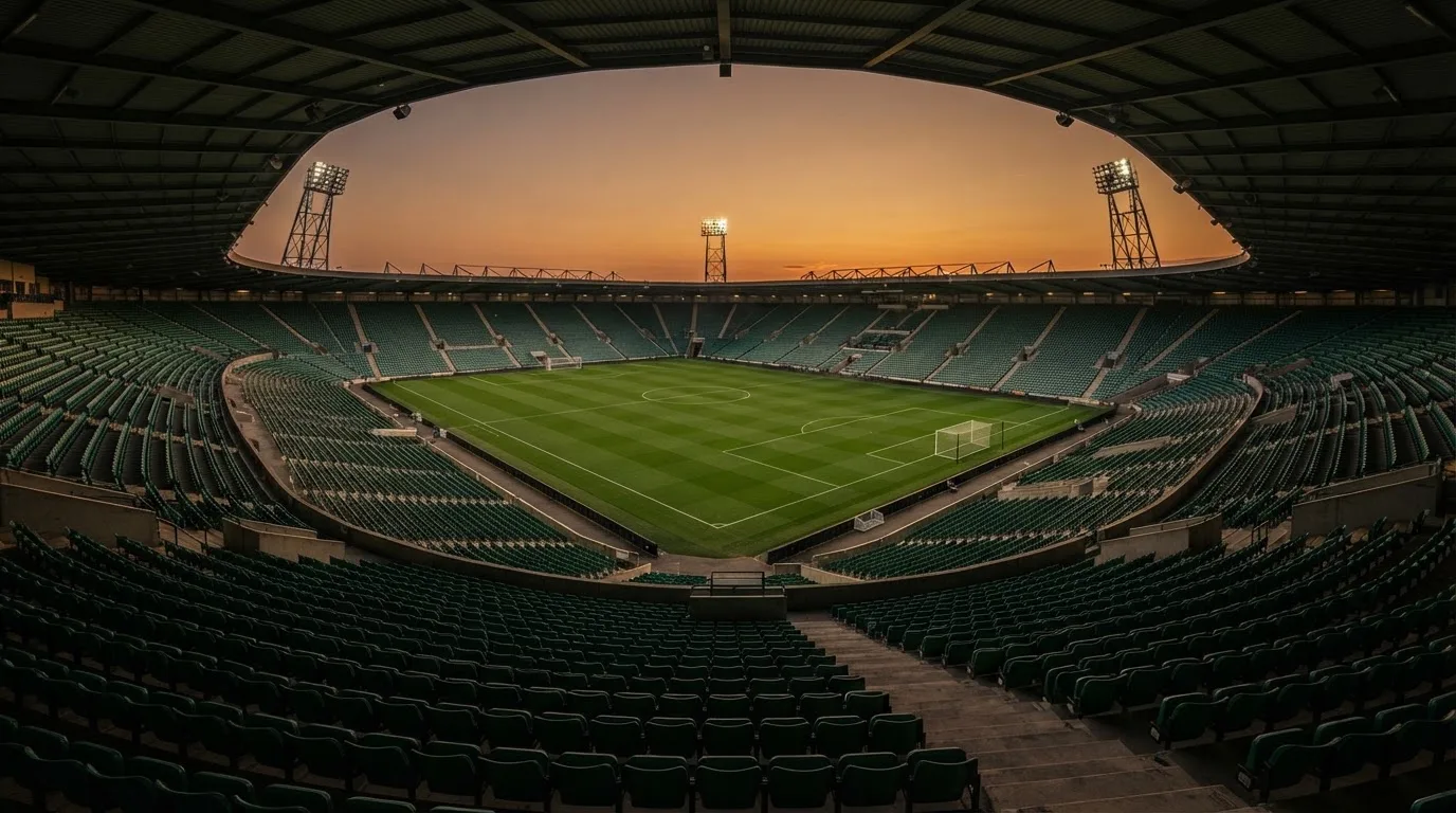 Un estadio de fútbol vacío con torres de iluminación al atardecer
