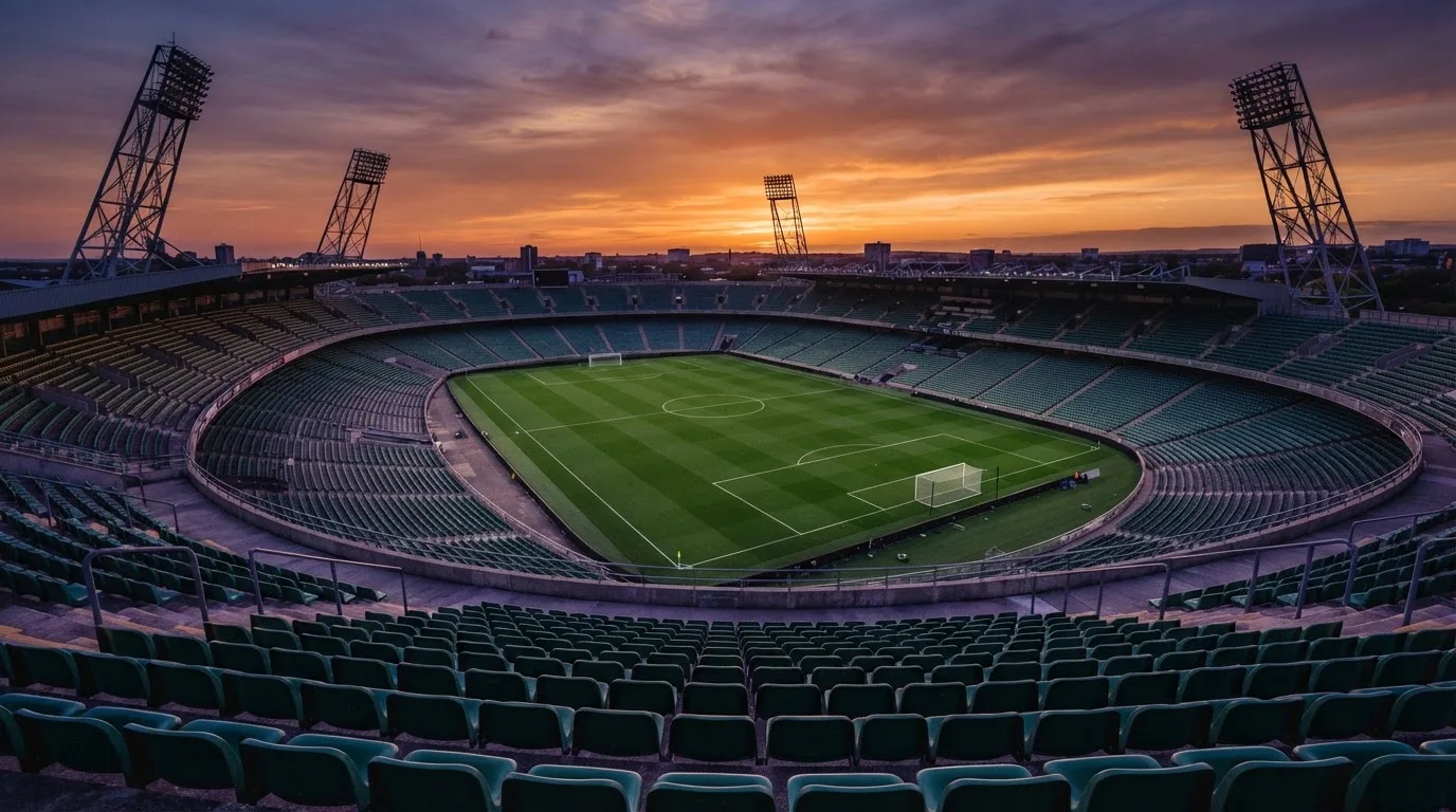 Un estadio de fútbol vacío con torres de iluminación al atardecer