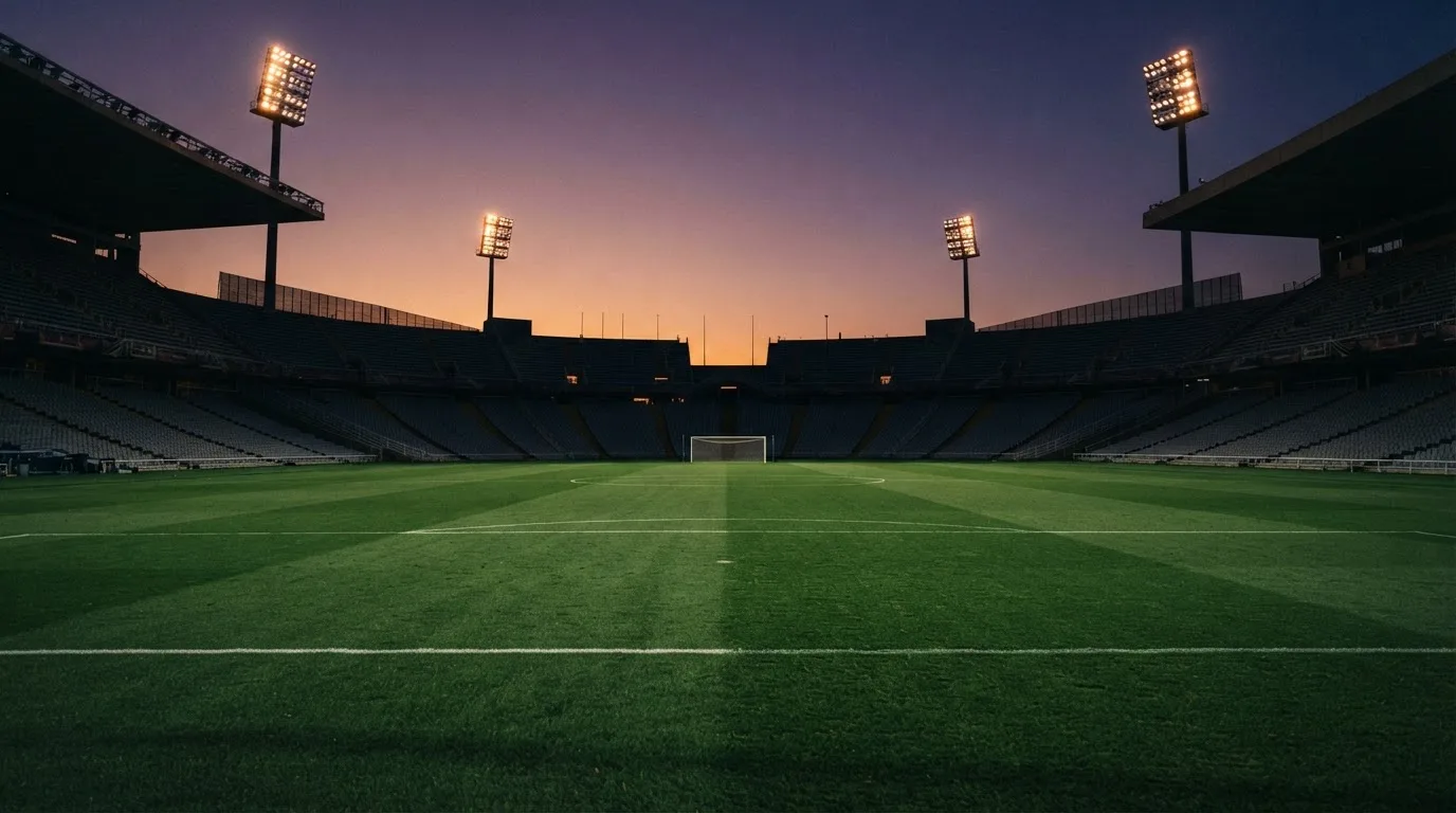 Un estadio de fútbol vacío con torres de iluminación al atardecer