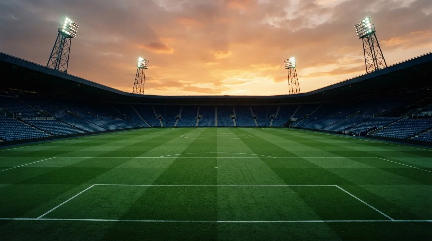 Un estadio de fútbol vacío con torres de iluminación al atardecer